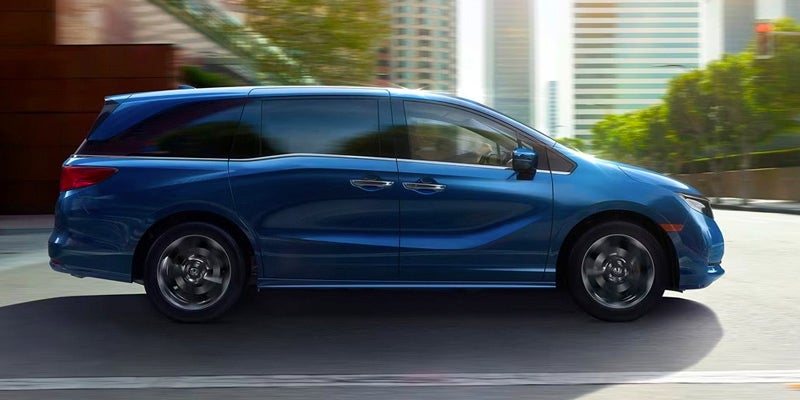 An All-New 2024 Obsidian Blue Peral Honda Odyssey driving through downtown Oxford, NC.