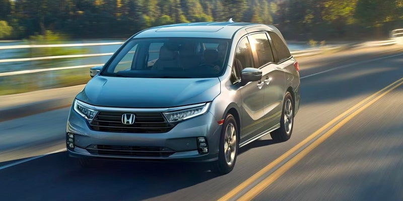 An all-new 2024 Silver Honda Odyssey driving down a rural road. - Boyd Honda Oxford, NC
