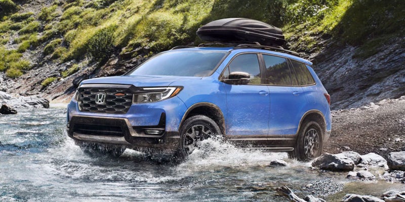 A 2024 Blue Honda Passport crossing a stream on a backroad through the mountains. - Boyd Honda Oxford, NC