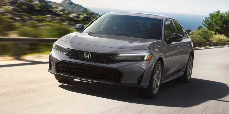 An all-new grey 2025 Honda Civic Sedan cruising along an oceanside highway. - Boyd Honda Oxford, NC