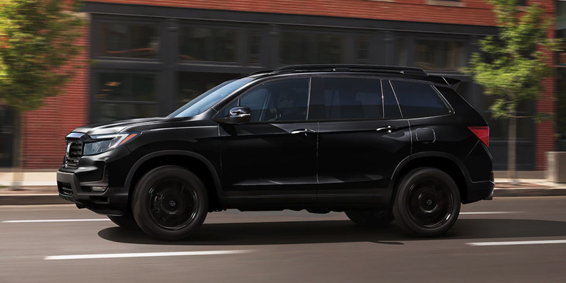 An all-new black 2025 Honda Passport driving through a downtown setting. - Boyd Honda Oxford, NC