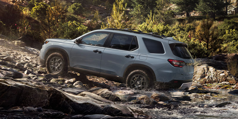 An all-new grey 2025 Honda Pilot crossing a shallow-rocky stream on a mountain back trail. - Boyd Honda Oxford, NC