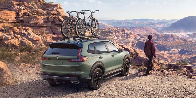 2026 Honda CR-V Hybrid Mounted with 2 bicyles with a man next to it enjoying the scenic view