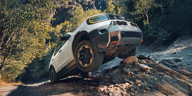 A white truck drives along a rocky trail