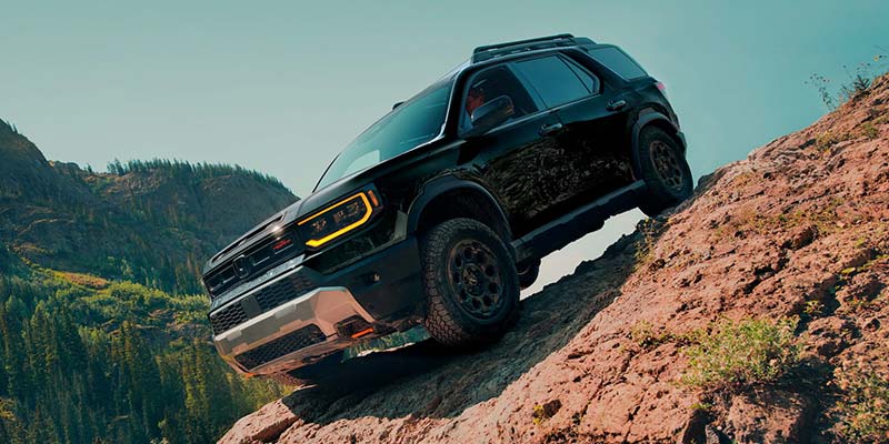 2026 Honda Passport driving down a steep rocky slope in a scenic mountain landscape, showcasing its off-road capability