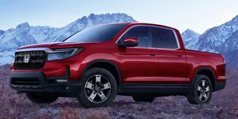 A red Honda Ridgeline parked in front of a snowy mountain range.